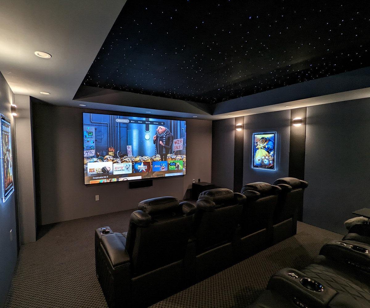 Compact gray screening room with black recliners and a recessed starlight ceiling