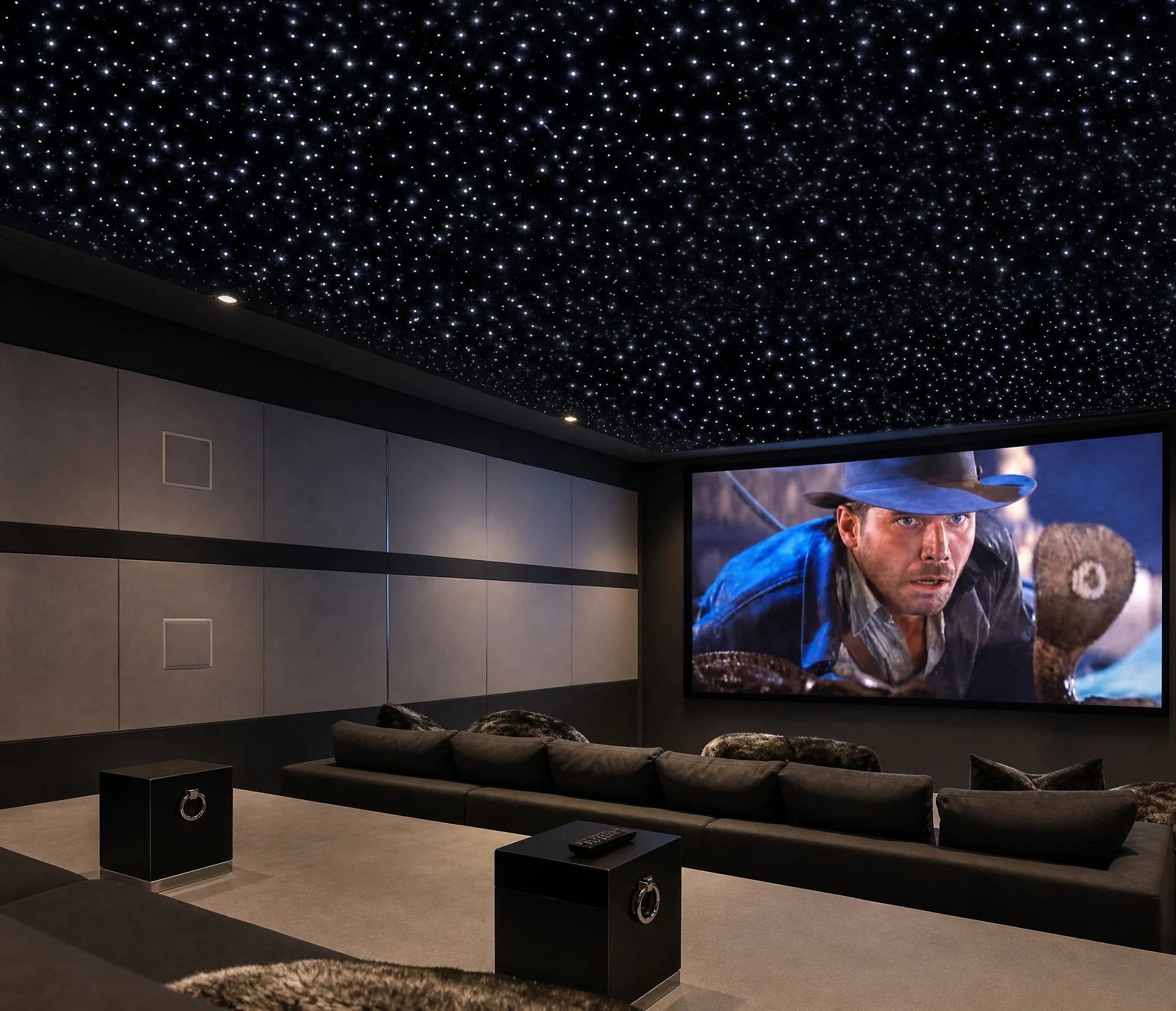 Minimal black home theater with a large screen, long sofa, and dense white starlight ceiling